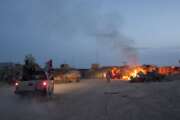 FILE - An Afghan National Army pickup truck passes parked U.S. armored military vehicles, as smoke rises from a fire in a trash burn pit at Forward Operating Base Caferetta Nawzad, Helmand province south of Kabul, Afghanistan, April 28, 2011. The Senate is expected to approve on Thursday a large expansion of health care and disability benefits for veterans of Iraq and Afghanistan in response to concerns about their exposure to toxic burn pits.  (AP Photo/Simon Klingert, File)