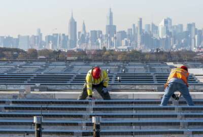 FILE - Framed by the Manhattan skyline, electricians with IBEW Local 3 install solar panels on top of the Terminal B garage at LaGuardia Airport, Nov. 9, 2021, in the Queens borough of New York. President Joe Biden is promising “strong executive action” to combat climate change, despite dual setbacks that have restricted his ability to regulate carbon emissions and boost clean energy such as wind and solar power. (AP Photo/Mary Altaffer, File)