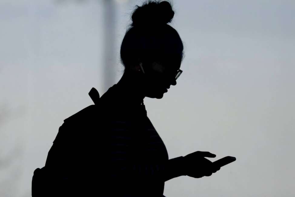 FILE - A woman checks her phone in Orem, Utah, on Nov. 14, 2019. A survey of people ages 16 to 40 finds that millennials and Generation Z follow the news, but they aren't that happy with what they're seeing. The study conducted by The Associated Press-NORC Center for Public Affairs Research and the American Press Institute says 79% of people follow news daily, contrary to perceptions that many are tuned out. (AP Photo/Rick Bowmer, File)