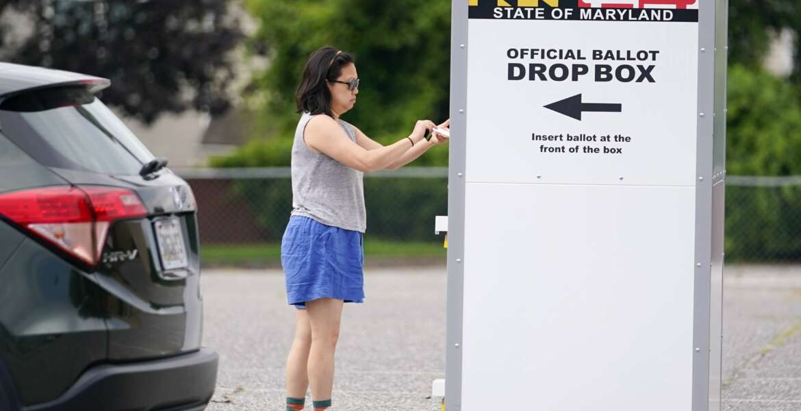 FILE - A woman drops a ballot into a drop box while casting her vote during Maryland's primary election, Tuesday, July 19, 2022, in Baltimore. The Maryland State Board of Elections voted Monday, Aug. 15, 2022, to file an emergency petition in court that seeks an earlier count of mail-in ballots for the general election in November. (AP Photo/Julio Cortez, File)