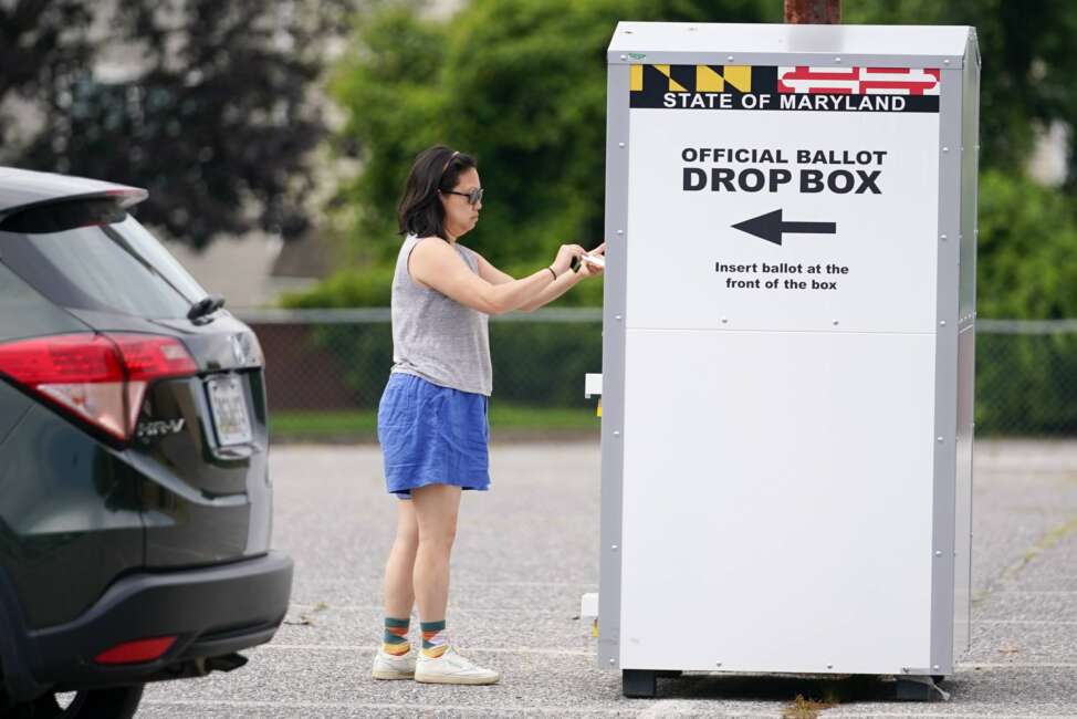 FILE - A woman drops a ballot into a drop box while casting her vote during Maryland's primary election, Tuesday, July 19, 2022, in Baltimore. The Maryland State Board of Elections voted Monday, Aug. 15, 2022, to file an emergency petition in court that seeks an earlier count of mail-in ballots for the general election in November. (AP Photo/Julio Cortez, File)