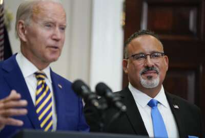 Education Secretary Miguel Cardona listens as President Joe Biden speaks about student loan debt forgiveness in the Roosevelt Room of the White House, Wednesday, Aug. 24, 2022, in Washington. (AP Photo/Evan Vucci)