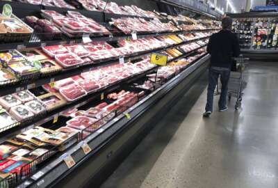 FILE - In this May 10, 2020 file photo, a shopper pushes his cart past a display of packaged meat in a grocery store in southeast Denver. Prices at the wholesale level fell from June to July, the first month-to-month drop in more than two years and a sign that some of the U.S. economy's inflationary pressures cooled last month. Thursday’s report from the Labor Department showed that the producer price index — which measures inflation before it reaches consumers — declined 0.5% in July. (AP Photo/David Zalubowski, File)