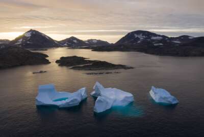 FILE - Large Icebergs float away as the sun rises near Kulusuk, Greenland, Aug. 16, 2019. The Biden administration said Friday, Aug. 26, 2022, that it will upgrade its engagement with the Arctic Council and countries with an interest in a region that's rapidly changing due to climate change. (AP Photo/Felipe Dana, File)