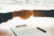 Business people negotiating a contract handshake between two colleagues