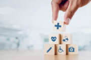 Close up man hand arranging wood block with healthcare medical icon on hospital background. Health care and Health insurance concept.