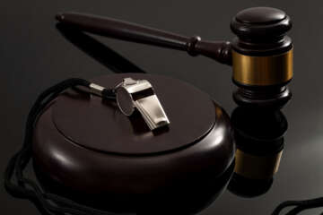 Whistleblower protection law and freedom of information legislation conceptual idea with metal whistle and wooden judge gavel on dark background