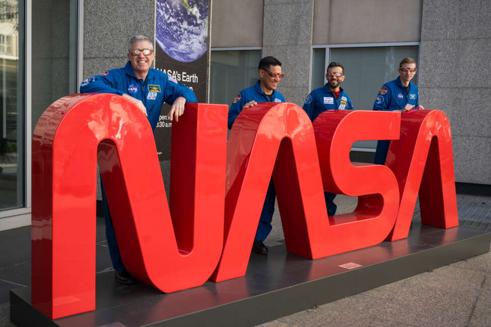 Image of NASA astronauts wearing solar eclipse glasses in front of NASA building in Washington, D.C.