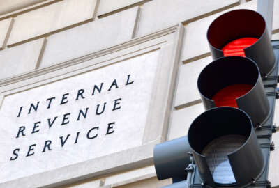 IRS sign with a traffic signal in the foreground indicating a red light.