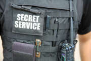 U.S. Secret Service officer, wearing a vest with various equipment attached, stands in front of White House. Washington DC. USA