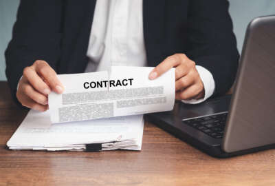 Businessman in a suit tearing up a contract while sitting at the table